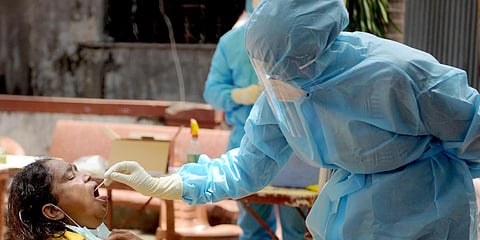 A health worker collects swab sample from a woman to test for COVID-19, at PMGP Colony in Dharavi. (Photo| ANI)