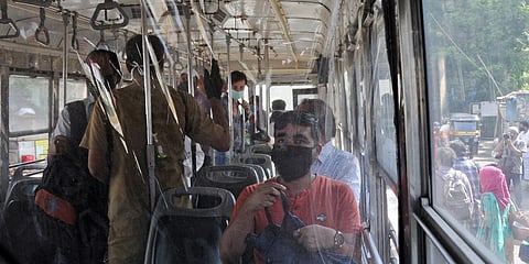 Passengers are seen seated inside the bus behind a plastic sheet as protection after easing in lockdown restriction, in Mumbai. (Photo| ANI)