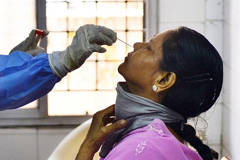 A health worker busy taking nasal swab from a woman for Covid-19 test at a Public Health Laboratory and Health Care Center. (Photo | Debdatta Mallick, EPS)