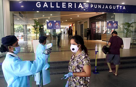 People seen giving the sanitizer and thermal check by wearing PPE suit to the customers who came to buy things outside to the Galleria Next mall at Punjagutta in Hyderabad. (Photo| EPS/Sathya Keerthi)