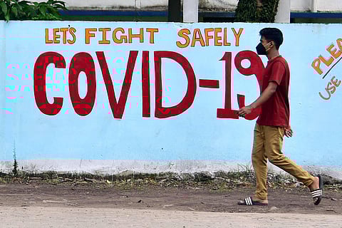 A boy passes by a coronavirus graffiti. (Photo| ANI)