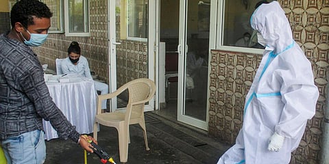 A worker disinfects the PPE suit of a medic during a COVID-19 rapid antigen testing camp in Gurugram. (Photo| PTI)