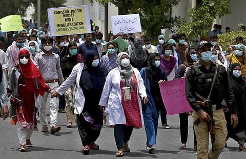 A police officer guards health workers marching towards the office of the Chief Minister of Sindh Province, during a rally demanding job regularizations and payment of outstanding wages, in Karachi, Pakistan, Monday, July 6, 2020. (Photo | AP)