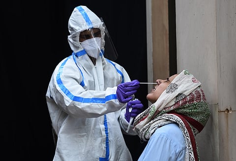 A healthcare worker wearing Personal Protective Equipment takes a swab of a woman to test for the coronavirus COVID-19. (Photo | Parveen Negi, EPS)
