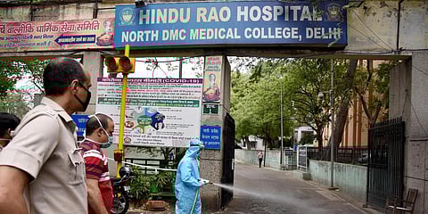 Municipal workers splash disinfectant and sanitizer at the Hindu Rao Hospital. (Photo| ANI)