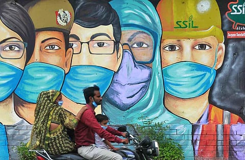 A man rides past a wall mural painted to thank frontline workers fighting the Covid-19. (File Photo | Shekhar Yadav, EPS)