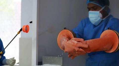A health worker sanitizes the gloves of another inside a booth after he collects sample of a person for COVID-19 test at a testing Centre in New Delhi on Saturday. (Photo | Shekhar Yadav/EPS)