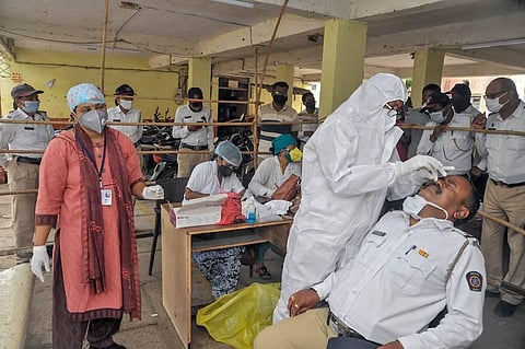 A medic collects swab sample of a policeman for COVID-19 test after the authorities again imposed lockdown due to surge in coronavirus cases in Sangli Thursday July 23 2020. (Photo | PTI)
