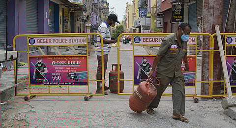 A gas agency employee delivers cylinders to residents of a containment  zone near Begur, in Bengaluru. (Photo | Meghana Sastry, EPS)