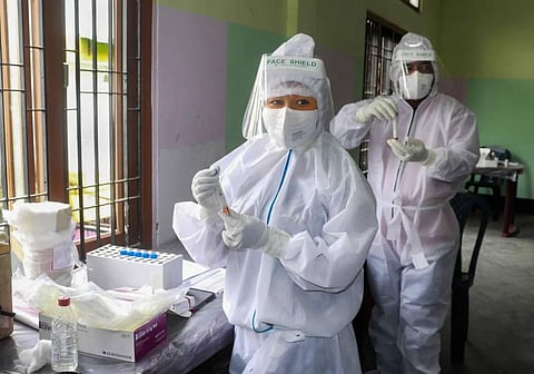 Health workers wearing PPE hold samples for COVID-19 rapid antigen testing in Sonitpur district of Assam on Tuesday. (Photo | PTI)