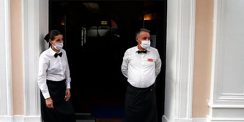 Waiters, wearing protective face masks in front a restaurant in Belgrade, Serbia. (Photo | AP)