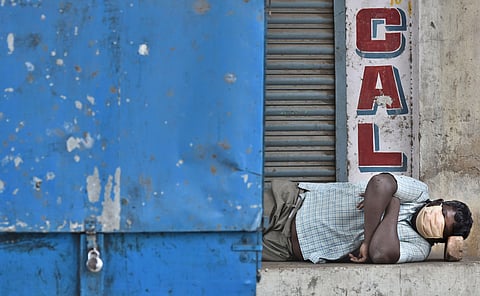 A man sleeps beside a locked streetside cart. (File Photo |  P Jawahar, EPS)