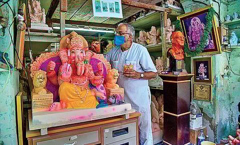 An artisan wearing a face mask paints a clay idol of Lord Ganesh at a workshop in Mumbai. (File| AFP)