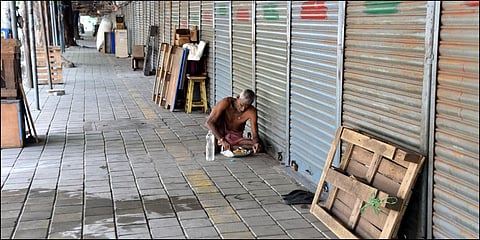 A man having food near closed shops at Burma Bazaar during a complete Sunday lockdown in Chennai. (File photo| R Satish Babu, EPS)