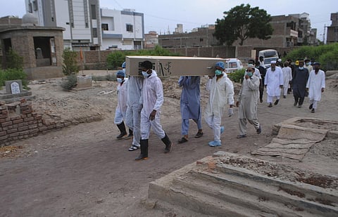 Rescue workers and family members carry the casket of COVID-19 victim. (Photo | AP)