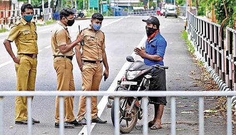 A motorist pleading to the police not to fine him for riding his bike without a valid reason during the triple lockdown. A scene from Vetturoad near  Kazhakootam, Thiruvananthapuram. (Photo | B P Deepu, EPS)