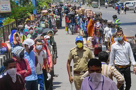 Migrants wait in queues before boarding a bus to the railway station during the ongoing nationwide COVID-19 lockdown in Surat Wednesday May 27 2020. (File | PTI)