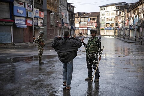 A paramilitary soldier orders a Kashmiri to open his jacket before frisking him during curfew in Srinagar. (Photo | AP)