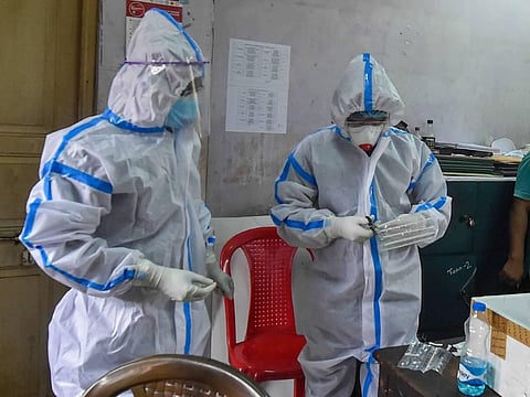Health technicians collect swab samples for COVID-19 tests from the workers at a health centre in Kolkata (Photo | PTI)