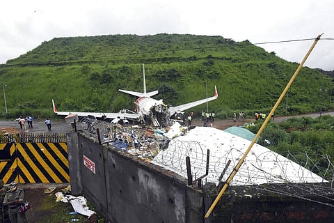 Officials stand by the debris of the Air India Express flight that skidded off a runway while landing in Kozhikode, Kerala state, India, Saturday, Aug. 8, 2020.  (Photo | AP)