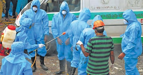 Fire fighters and medical staff getting themselves sanitised after transporting bodies of the victims from the Covid care centre to a mortuary, in Vijayawada on Sunday. (Photo | Prasant Madugula, EPS)