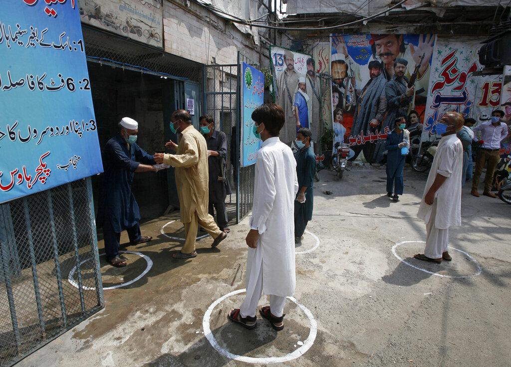 People wear face masks and keep social distancing as they enter a cinema following an ease in restrictions that had been imposed to help control the coronavirus, in Peshawar. (Photo | AP)