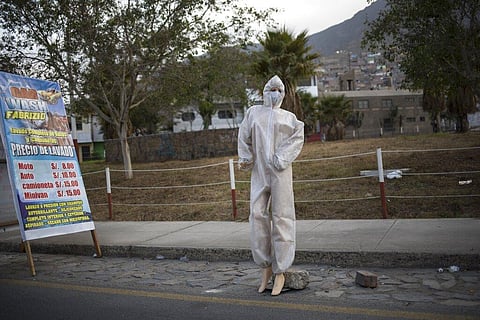 A mannequin dressed in protective gear due to the COVID-19 pandemic, is deployed in front of a car wash to attract customers, in Lima, Peru, Monday, Aug. 10, 2020. (Photo | AP)