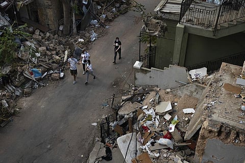 People walk next debris from destroyed buildings on a neighborhood near the site of last week's explosion that hit the seaport of Beirut, Lebanon. (Photo | AP)