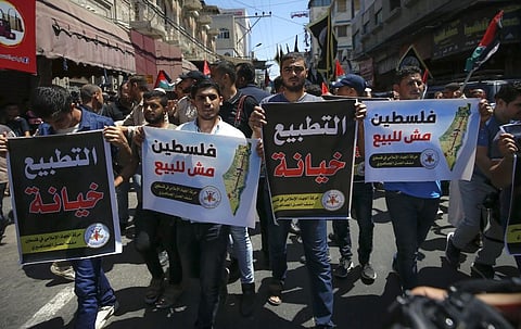 Palestinian protesters hold slogans reading in Arabic 'normalisation is betrayal' and 'Palestine is not for sale' during a demonstration in Gaza City on August 14. (Photo | AFP)
