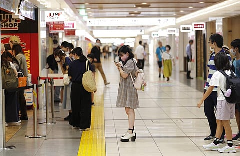 Shoppers wait outside a store as a limited number of customers are allowed into the store at a time at a shopping center in Tokyo. (Photo | Japan)