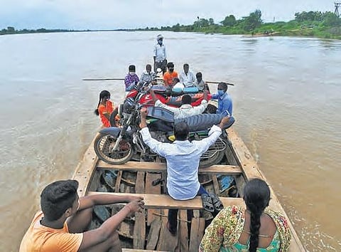 With most roads submerged in rain water, people use a boat to cross a channel near Vijayawada on Sunday (PHOTO | PRASANT MADUGULA, EPS)