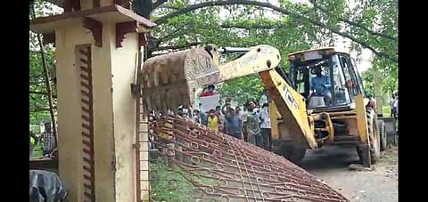 Protesters pulling down the concrete gate at the Poush Mela ground using a bulldozer (Photo | EPS)