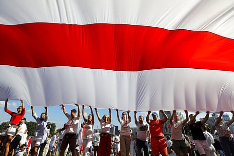 In this Sunday, Aug. 16, 2020 file photo opposition supporters wave a huge old Belarusian national flag as they rally in the center of Minsk, Belarus. (Photo | AP)
