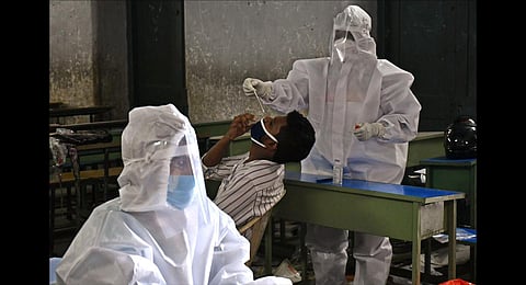 A health worker collects the swab sample for COVID testing at a classroom in Vijayawada's Gandhi Municipal High School. (Photo | Prasant Madugula, EPS)