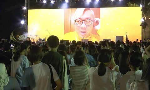 Pavin Chachavalpongpun, administrator of the Facebook group “Royalist Marketplace,” is shown delivering a pre-recorded message onscreen before a crowd attending an anti-government rally (Photo | AP)