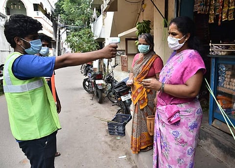 A corporation staff checks the temperature at the doorstep of the resident in Valasaravakkam where the COVID-19 casses are in rise. (Photo | P Jawahar/EPS)