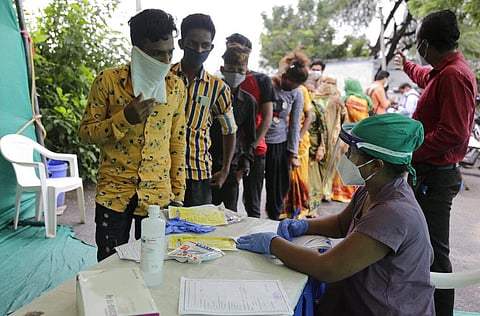A health worker takes details of people standing in a queue to test for COVID-19 at a check post erected to screen people coming from outside the city, in Ahmedabad, India. (Photo | AP)