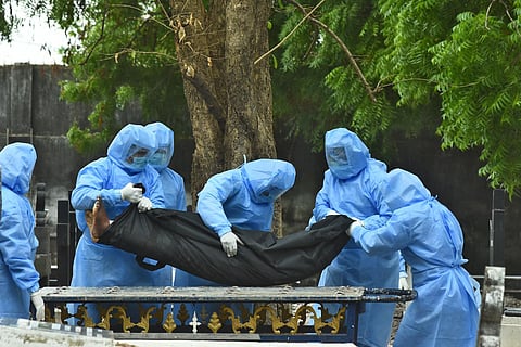 Volunteers wearing personal protective equipment carrying the body of a COVID-19 victim at a cemetry in St Thomas mount on Thursday. (Photo | Ashwin Prasath, EPS)