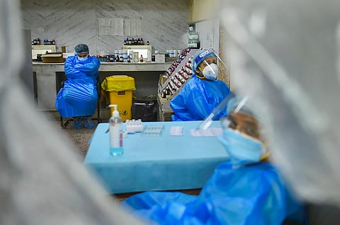 Health workers rest at a COVID-19 testing centre after duty. (File Photo|PTI)