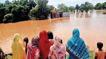 People watch as flood water gushes into  Mirjapur village of Dasarathpur block