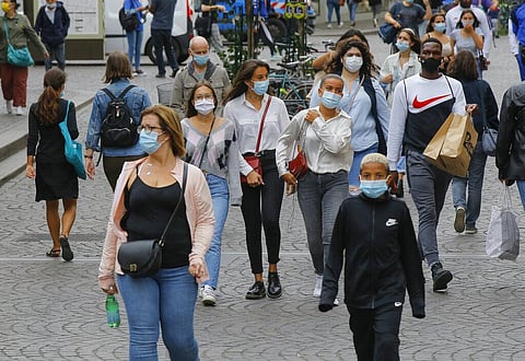 People walk in a shopping area while wearing a protective face masks as a precaution against the coronavirus in Paris. (Photo | AP)
