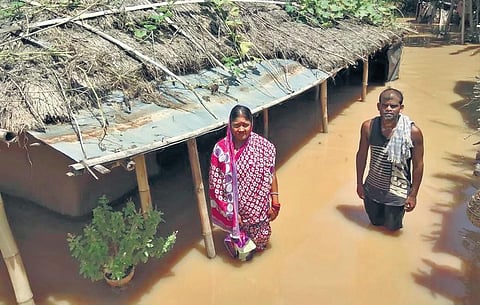 A couple stand in front of their house that has been submerged in flood water in a village in Bari block of Jajpur | akshya rout