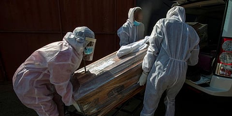 Funeral home workers in protective suits carry the coffin of a woman who died from COVID-19 into a hearse in Katlehong, near Johannesburg, South Africa. (Photo | AP)