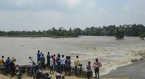 Villagers stand on a locked culvert near the flooded area at Balakati area in Bhubaneswar. (Photo | PTI)
