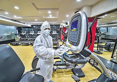 A worker sanitizes gym equipments ahead of its reopening, in East Delhi | PTI