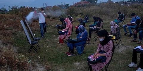 Muneer Alam, an engineer-turned-math teacher, sprays disinfectant before the start of an early morning outdoor class at Eidgah, a ground reserved for Eid prayers, in Srinagar. (Photo | AP)