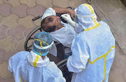 A medic collects samples from a person with physical disability for COVID-19 rapid antigen testing amid the complete bi-weekly lockdown to curb COVID-19 spread in Kolkata Saturday. (Photo | PTI)