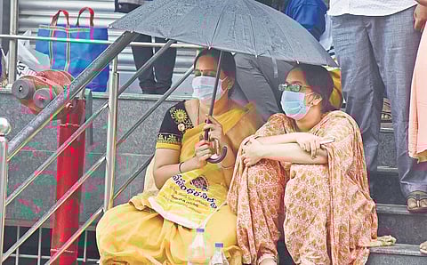 A woman holds an umbrella for her daughter during rain at an examination centre in Vijayawada on Sunday | P Ravindra Babu