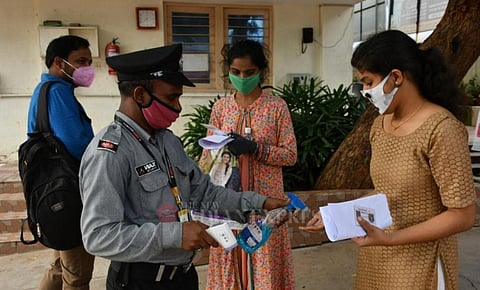 Staff provide sanitiser and check the temperature of students appearing for EAMCET exam in Vijayawada's KBN college. (Photo | Prasant Madugula, EPS)