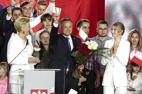 Polish President Andrzej Duda flashing a victory sign, with wife Agata Kornhauser-Duda, front left, and daughter Kinga Duda, front right, on the night of his re-election. (Photo | AP)